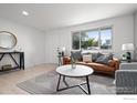 Cozy living room with a leather sofa, decorative pillows, a round coffee table, and modern decor at 5329 Flower Cir, Arvada, CO 80002