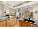 Well-lit kitchen featuring granite countertops, oak cabinets, stainless sink, and seamless flow to dining area at 735 Orchard Ct, Louisville, CO 80027