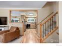 Cozy living room showcasing staircase, wood laminate flooring, and a view into the kitchen at 9852 Zephyr Dr, Broomfield, CO 80021