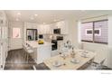 Modern white kitchen with stainless steel appliances and eat-in island next to the dining area at 10331 E 62Nd Pl, Denver, CO 80238