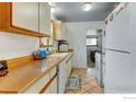 Well-lit kitchen with tile floors, white appliances, and ample counter space for cooking and meal prep at 1256 Ulster St, Denver, CO 80220