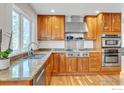 Gourmet kitchen featuring stainless steel appliances, granite countertops, wood cabinets, and a large window at 1427 Cannon Mountain Dr, Longmont, CO 80503