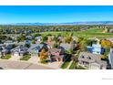 Expansive aerial view showcasing the neighborhood, nearby golf course, and distant mountain range at 1853 Rannoch Dr, Longmont, CO 80504