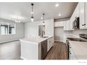 Modern kitchen features stainless appliances, white cabinets, quartz countertops, and wood flooring at 2267 Peregrine Dr, Brighton, CO 80601