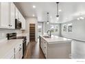 Open kitchen features white cabinets, quartz countertops, island, stainless steel appliances, and pantry at 2267 Peregrine Dr, Brighton, CO 80601