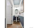 Stylish half bathroom with two-tone walls, a pedestal sink, an oval mirror and a light fixture at 4206 Sandstone Dr, Mead, CO 80504