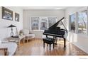 Elegant music room with a grand piano, hardwood floors, large windows, and comfortable seating at 5338 Pine Valley Ct, Boulder, CO 80301