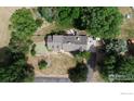 Aerial view of a house with mature trees, a pond, and a well-maintained yard at 620 Highway 52, Erie, CO 80516