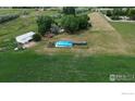 Aerial view of pool, barn, and house on expansive acreage with lush green grass at 620 Highway 52, Erie, CO 80516