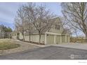 Spacious home with a three-car garage, green siding, mature trees, and large paved driveway at 620 Highway 52, Erie, CO 80516