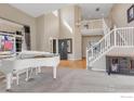 Sunlit living room featuring a piano, staircase, and a view of the front entry at 730 Pope Dr, Erie, CO 80516