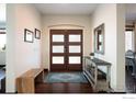 Inviting foyer featuring a wood floor, bench, console table, and front door with translucent rectangular glass insets at 16078 W Ellsworth Dr, Golden, CO 80401