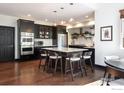 Modern kitchen with a center island with bar stool seating, dark cabinetry, and stainless steel appliances at 16078 W Ellsworth Dr, Golden, CO 80401