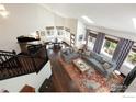 Open-concept living room with high ceilings, skylights, hardwood floors, and large windows with patterned curtains at 16078 W Ellsworth Dr, Golden, CO 80401