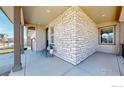 Inviting covered front porch with stone accent wall, offering a cozy outdoor seating area at 420 Pleades Pl, Erie, CO 80516