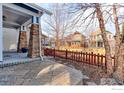 Inviting covered porch with stone pillars and a neatly paved patio, surrounded by a wooden fence at 5068 Uinta St, Denver, CO 80238