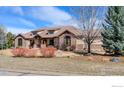 Charming single-story home featuring a tile roof, stone accents, and a neatly landscaped yard at 8604 Portico Ln, Longmont, CO 80503