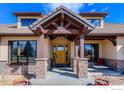 Inviting front porch with stone pillars, wood beams, and a wood door for an appealing entry at 8604 Portico Ln, Longmont, CO 80503