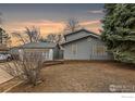 View of a gray home with mature trees, gray siding, and a manicured lawn at 911 Timber Ct, Longmont, CO 80504