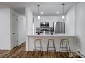 Modern kitchen featuring a breakfast bar with pendant lighting, stainless steel appliances, and white cabinetry at 14701 E Tennessee Dr # 132, Aurora, CO 80012