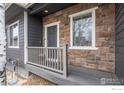 Inviting front porch with stone accents, and a gray front door with white trim at 1923 Windemere Ln, Erie, CO 80516