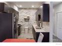 Modern kitchen features dark cabinets and stainless steel appliances with an eat-in dining area at 1401 W 85Th Ave # B-405, Denver, CO 80260