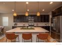 Modern kitchen featuring stainless steel appliances, a large island with seating, and elegant pendant lighting at 15325 W 93Rd Ave, Arvada, CO 80007