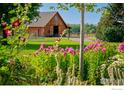 A barn is surrounded by green grass, with flowers in the foreground, and a distant fence at 2300 N 75Th St, Boulder, CO 80301