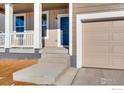 Close up of the front entrance showcasing a blue door, concrete steps, and a two car garage at 2718 Crystal Springs Ln, Longmont, CO 80503