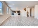 Spacious living room with hardwood floors, an open kitchen, and staircase access to the next level at 2718 Crystal Springs Ln, Longmont, CO 80503