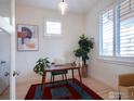 Bright home office featuring a wooden desk, modern art, and natural light streaming through the window at 906 Confidence Dr, Longmont, CO 80504