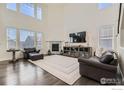 Elegant living room features soaring ceilings, a fireplace, dark wood floors, and large windows at 970 Compass Dr, Erie, CO 80516