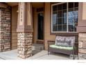 Inviting front porch with stone accents and a cozy bench to enjoy the outdoors at 13238 Ivy Ct, Thornton, CO 80602