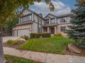 Well-maintained two-story home with stone and siding exterior, lush lawn, and mature trees at 14181 Whitney Cir, Broomfield, CO 80023