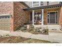 Inviting covered porch with seating, brick facade, and view of landscaped front yard at 1526 Chukar Dr, Longmont, CO 80504