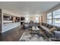 Open-concept living room featuring hardwood floors, a large sectional sofa, and abundant natural light at 2407 Tyrrhenian Cir, Longmont, CO 80504