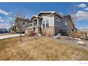 Stylish gray house with stone accents, well-maintained landscaping, and a partially fenced yard at 4877 Old River Ave, Firestone, CO 80504