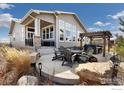 Outdoor patio featuring comfortable seating around a fire pit, complemented by lush landscaping at 4877 Old River Ave, Firestone, CO 80504