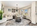 Bright living room featuring a bay window, neutral tones, decorative chandelier, and stylish furnishings at 6280 Snowberry Ave, Firestone, CO 80504