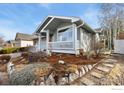 Low angle view of a charming home featuring a covered porch and rock-lined garden at 742 Megan Ct, Longmont, CO 80504