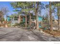 View of brick and grey home with beautiful landscaping, mature trees, and an asphalt driveway at 955 Jasmine Cir, Boulder, CO 80304