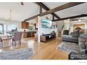 Open-concept living area featuring hardwood floors and exposed beams leading into the kitchen at 15757 Mossrock Ct, Longmont, CO 80503