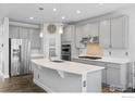 Bright kitchen features gray cabinets, stainless steel appliances, pendant lighting and large center island with quartz countertops at 1863 Pioneer Cir, Lafayette, CO 80026