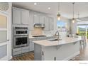 Kitchen features gray cabinets, stainless steel appliances and a large center island with quartz countertops at 1863 Pioneer Cir, Lafayette, CO 80026