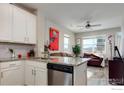 Modern kitchen featuring white cabinets, stainless steel appliances, granite countertops, and an open view to the living space at 2602 Tall Grass Trl, Berthoud, CO 80513