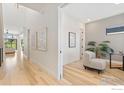 Bright hallway featuring hardwood floors, modern art, and a cozy seating nook near a window at 3364 Danzante Bay Ct, Berthoud, CO 80513