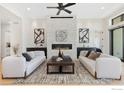 Stylish living room showcasing a stone fireplace, ceiling fan, and two plush white sofas at 3364 Danzante Bay Ct, Berthoud, CO 80513