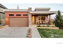 Modern home with a two-car garage, stone accents, inviting covered porch, and well-maintained landscaping at 1806 Blue Star Ln, Louisville, CO 80027