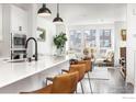 Bright open concept living room featuring modern white cabinets and a breakfast bar with brown leather barstools at 417 Promenade Dr, Superior, CO 80027