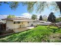 Spacious backyard with a covered patio, lush green grass, and mature trees at 2 Lincoln Pl, Longmont, CO 80501